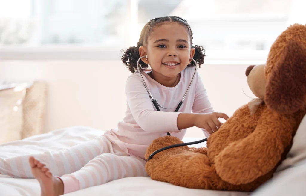Children, stethoscope and teddy bear with a girl playing doctor in her bedroom at home with a stuffed animal.
