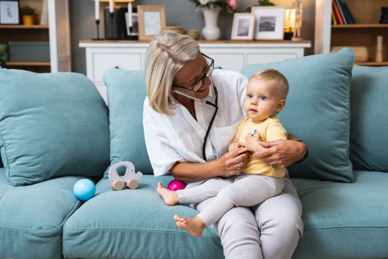 Grandmother retired woman doctor pediatric using stethoscope listening her grandson or granddaughter, young baby child lungs to check her medical condition and health situation.